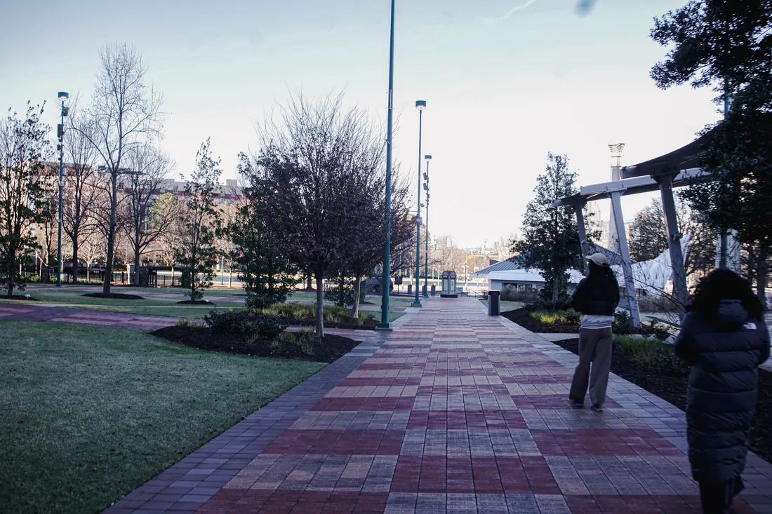 A long brick path through a park, with the stadium area ahead