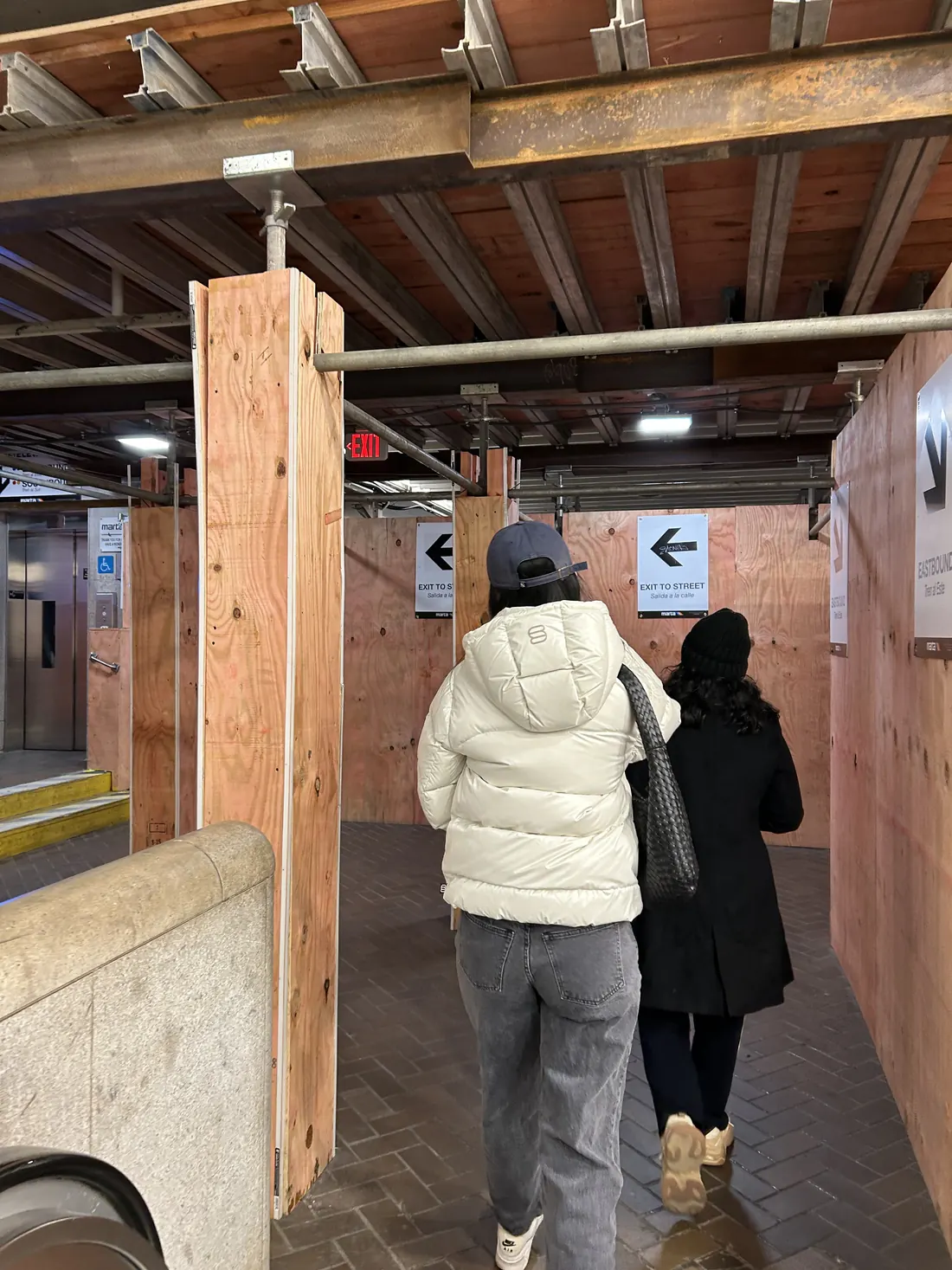 Two people following an arrow sign through a covered wooden walkway