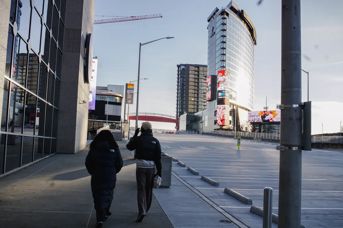 Two people walking a downtown street toward a tall hotel tower