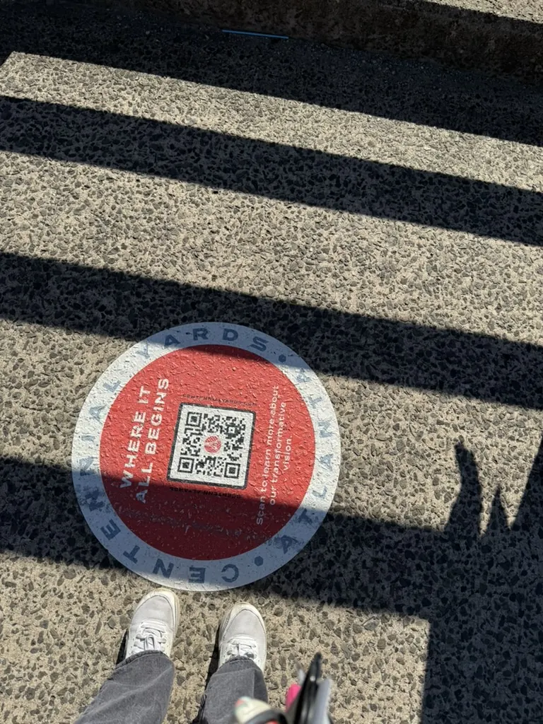A red QR code sticker on the pavement used as a wayfinding marker